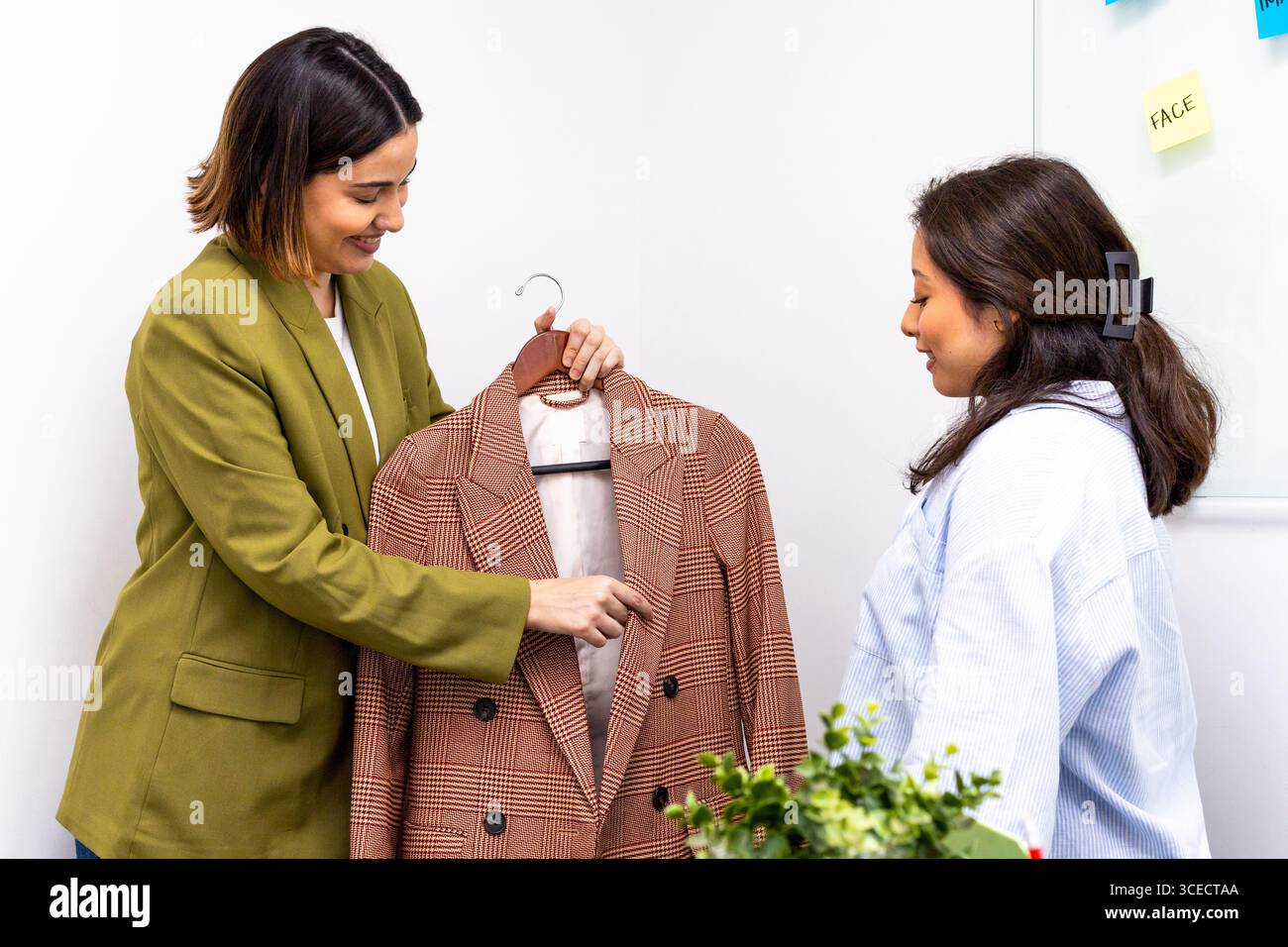 Image Consultants diskutieren über einen stylischen Blazer und verweisen dabei auf persönliche Branding- und Modeberatung. Ihre Interaktion spiegelt moderne Beratungstechnologie wider Stockfoto