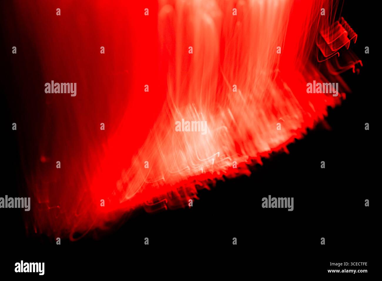 Eine dynamische Darstellung von roten Lichtspuren vor dunklem Hintergrund erzeugt ein Gefühl von Bewegung und Energie. Die Technik der Langzeitbelichtung hebt hervor Stockfoto
