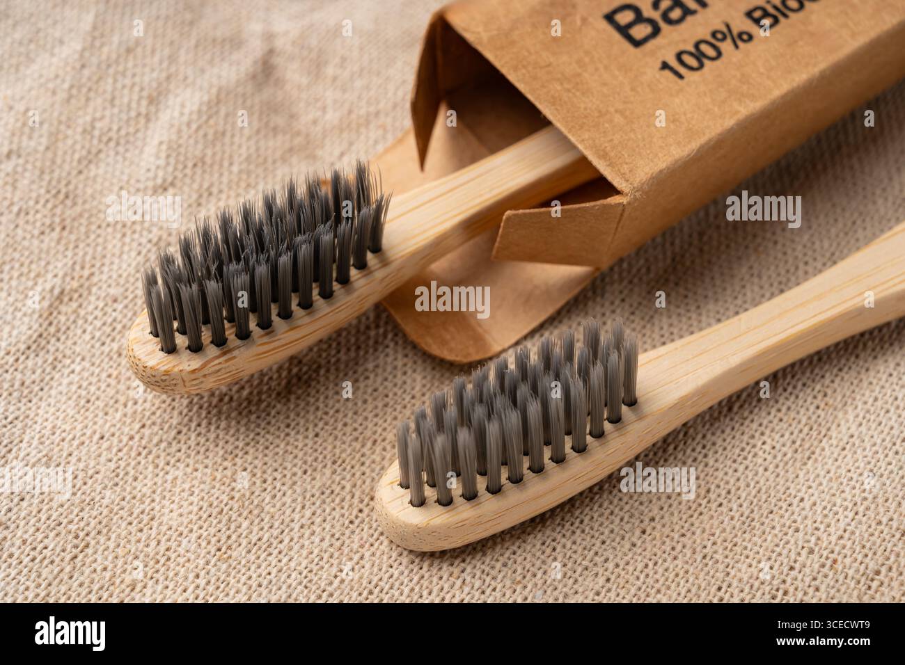 Von oben sehen Sie Bambus-Zahnbürsten auf einem strukturierten Sackleinen-Hintergrund mit umweltfreundlichen Toilettenartikeln. Mit natürlichen Farben und nachhaltigem Material Stockfoto