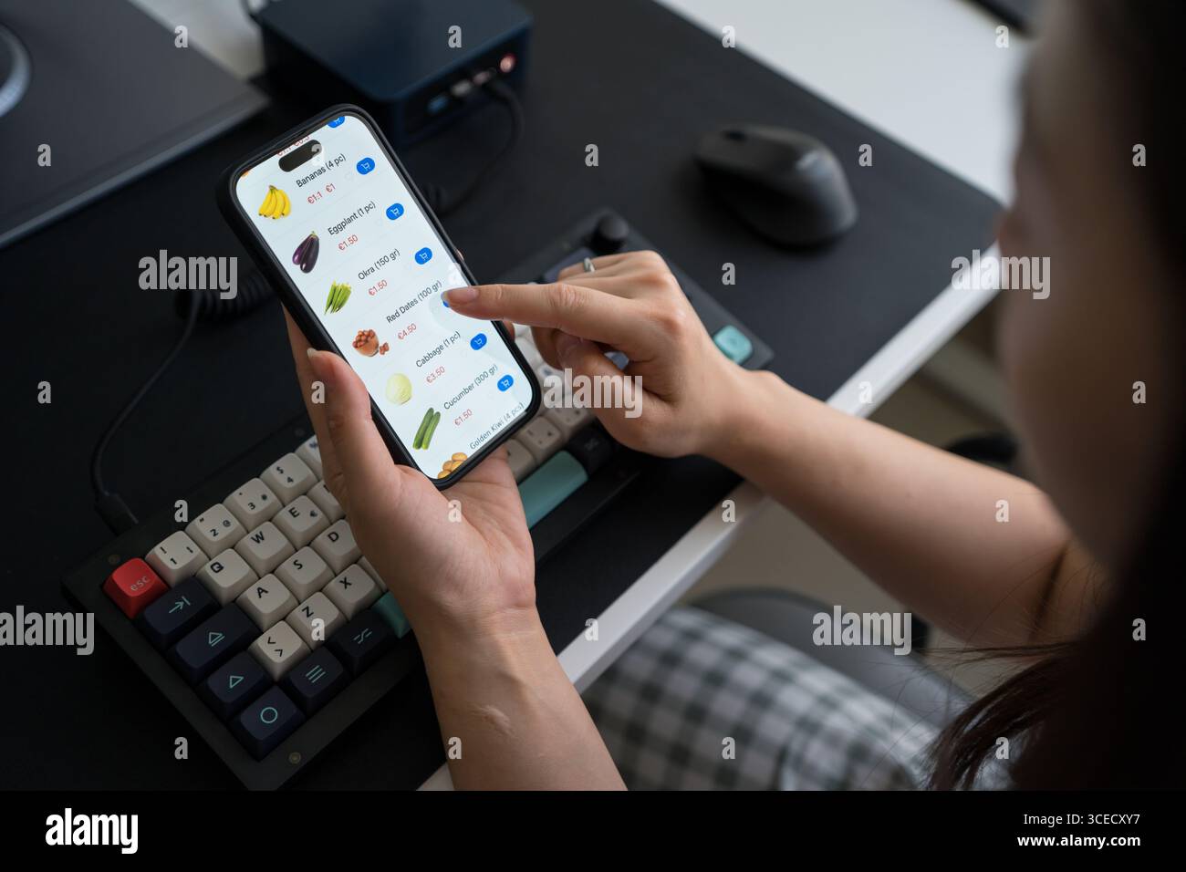 Beschnittene unerkennbare Frau, die ein Smartphone für Lebensmitteleinkäufe von zu Hause aus verwendet, zeigt einen digitalen Lebensstil mit einem Fokus auf gesunde Ernährung und Onli Stockfoto