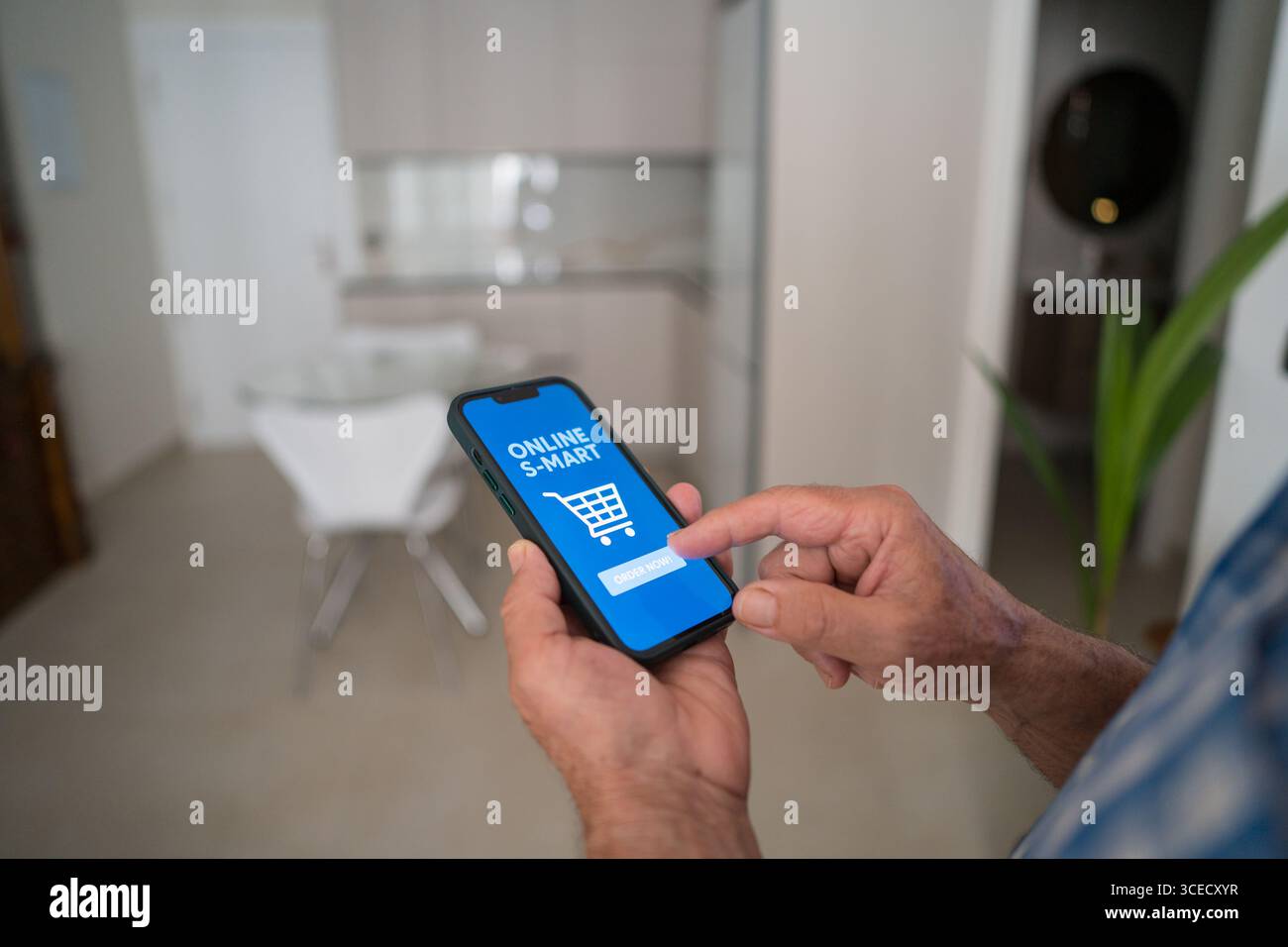 Abgeschnittener, nicht erkennbarer Seniorenmann, der ein Smartphone verwendet, um von zu Hause aus online einzukaufen. Auf der App-Oberfläche wird ein Online-Warenkorb angezeigt, der den Komfort unterstreicht Stockfoto