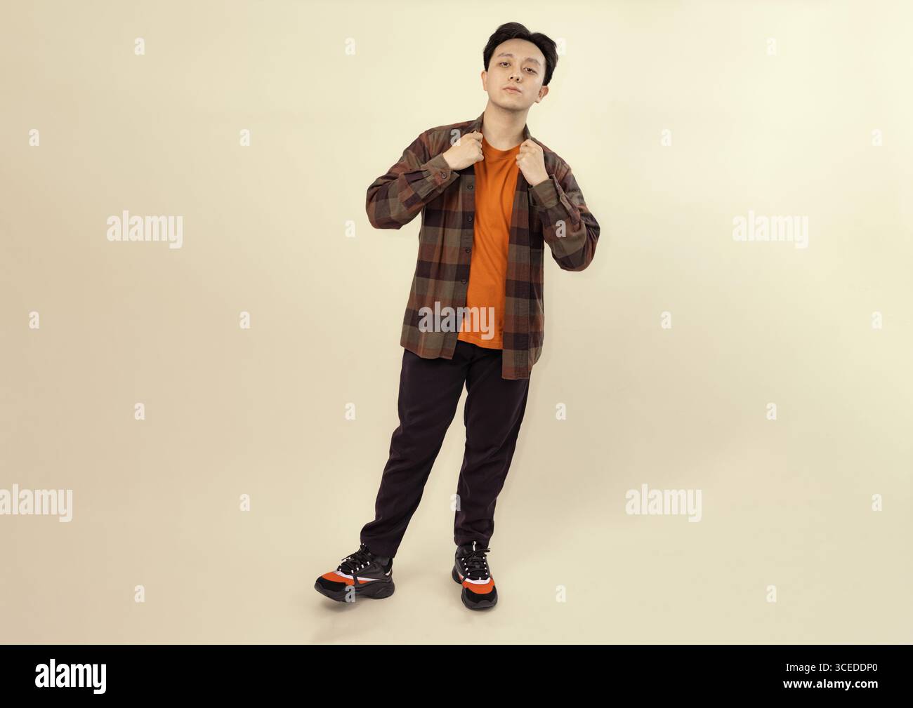 Junger erwachsener Mann in lässiger Kleidung posiert vor neutralem Hintergrund Stockfoto