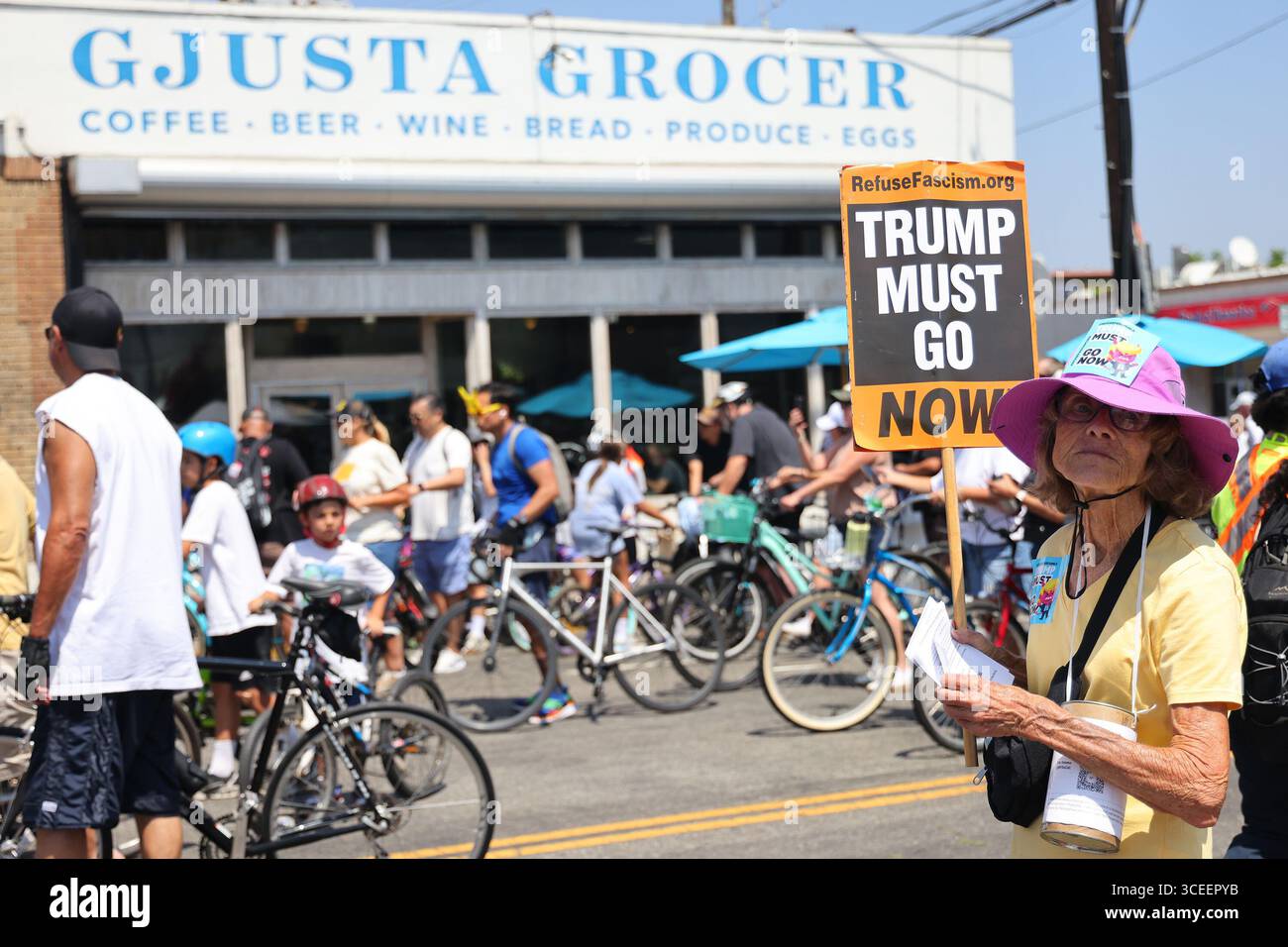 Venedig, Kalifornien, USA. August 2025. Eine Frau hält ein Anti-Trump-Schild, während die Teilnehmer am 61 Sonntag, den 18. August 2025, in Venedig an Gjusta Grocer auf der Windward Avenue vorbeifahren. Die Strecke erstreckte sich vom La Cienega Boulevard bis zum Venice Beach Boardwalk. (Credit Image: © Jonathan Alcorn/ZUMA Press Wire) NUR REDAKTIONELLE VERWENDUNG! Nicht für kommerzielle ZWECKE! Quelle: ZUMA Press, Inc./Alamy Live News Stockfoto