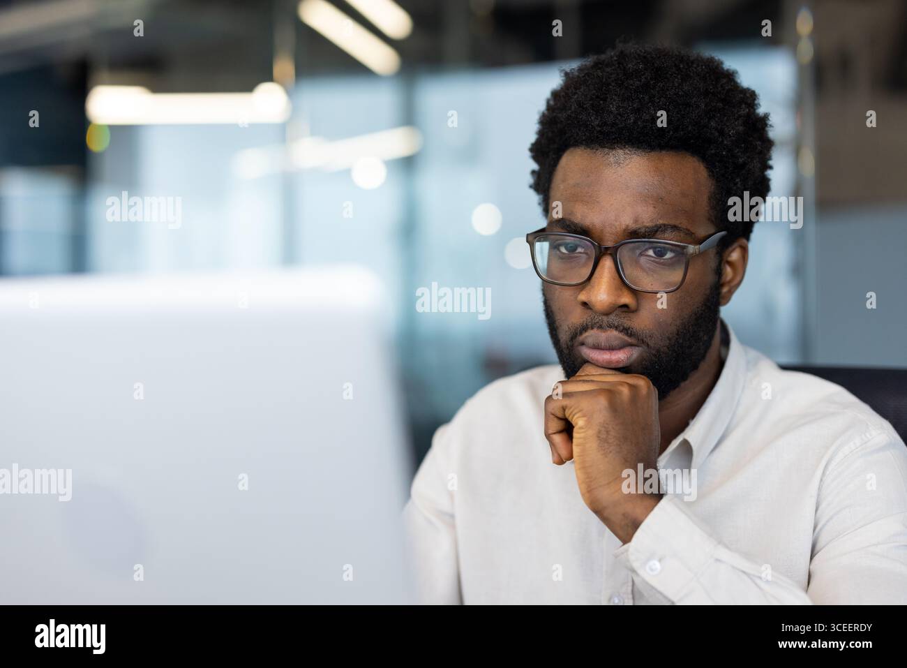 Eine professionelle Person, die sich bei der Arbeit an einem Computer in einem modernen Bürobereich intensiv konzentriert und Produktivität und Entschlossenheit ausstrahlt. Stockfoto