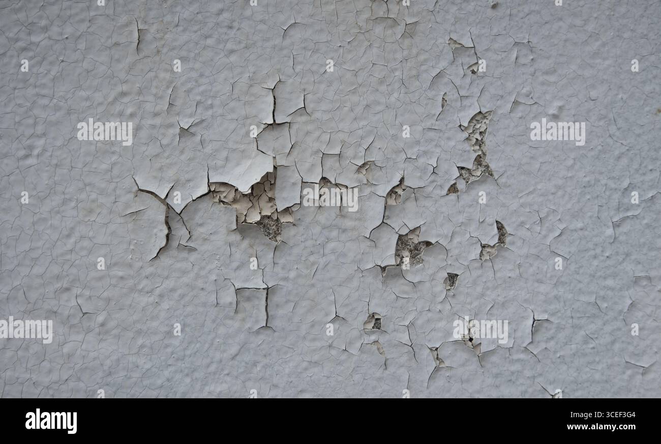 Hintergrundstruktur der abblätternden Farbe auf einer Zement- oder Putzwand weiße Farbe löst sich ab, um die Schicht unter der alten verwitterten Schicht freizulegen, die reparaturbedürftig ist Stockfoto
