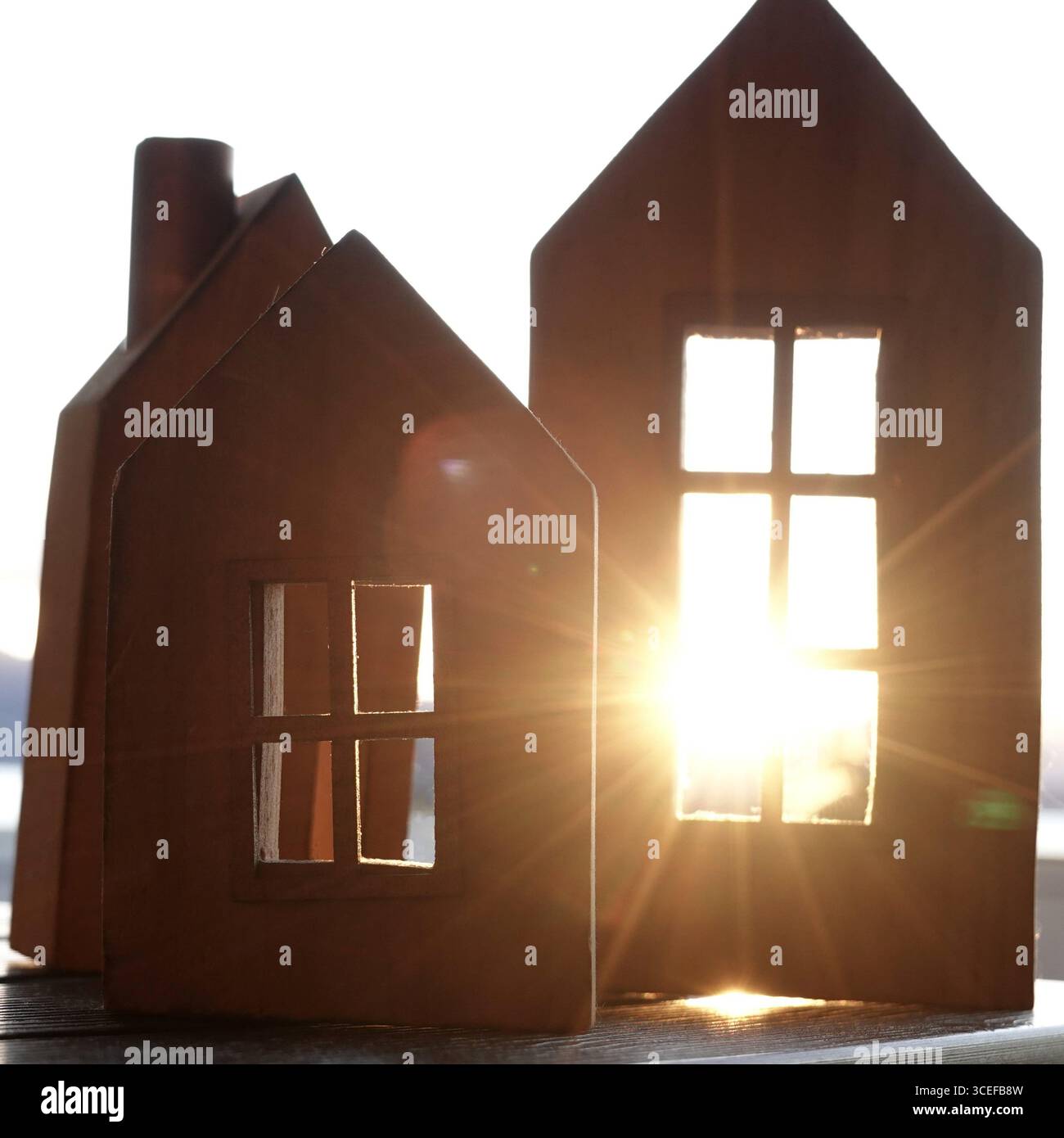 3 hölzerne Häuserblöcke im europäischen Stil mit Fenstern, durch die der Sonnenuntergang hindurchfliegt. Wohnungsbauverleih oder Wohnungsbau Stockfoto