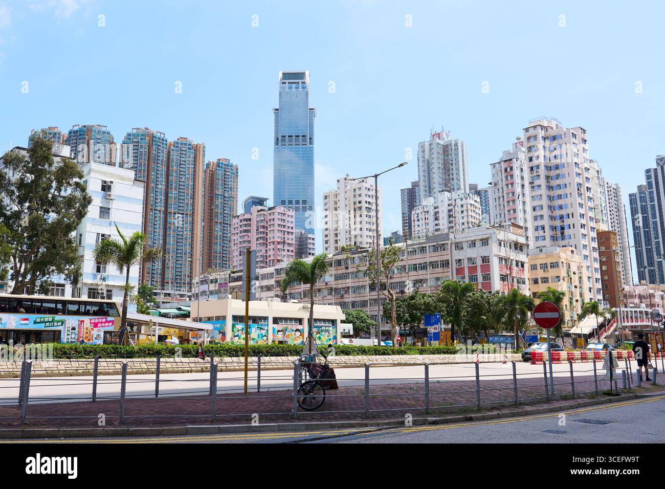 Eine Straßenszene des sonnigen Tsuen Wan von der Tai Chung Road, die das hohe neue Gebäude und ältere kurze Wohngebäude zusammen im Bezirk zeigt. Stockfoto