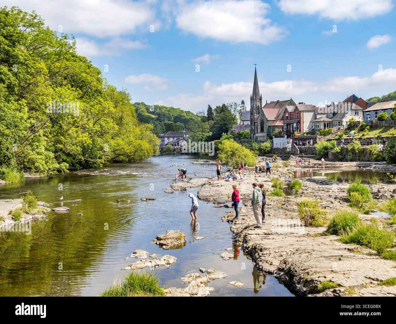 Llangollen und der Fluss Dee. Eine von vielen angenehmen Möglichkeiten, Zeit in der Stadt zu verbringen, diese riesigen Felsplatten im Fluss sind perfekt zum Entspannen oder... Stockfoto