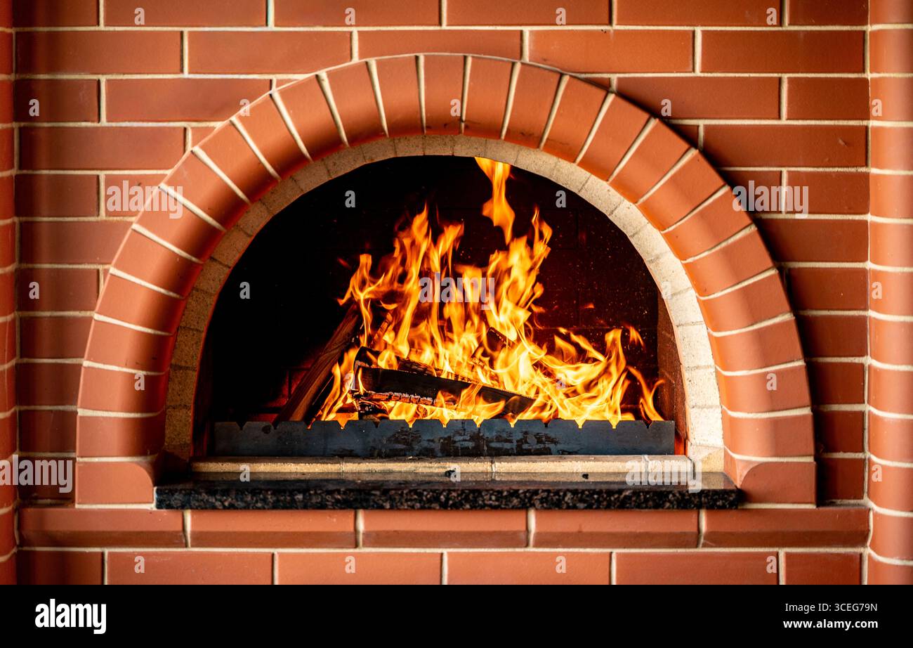 Heißes Brennholz in einem traditionellen Ofen, komfortable und warme Atmosphäre zu Hause, Hygge Konzept, Zubereitung von Speisen im klassischen Ofen, Winterferien Stockfoto