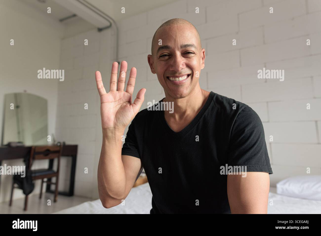 POV-Ansicht eines kahlköpfigen hispanischen Mannes in den 40ern in seinem Haus, der Videoanrufe hatte und die Hand winkte Stockfoto