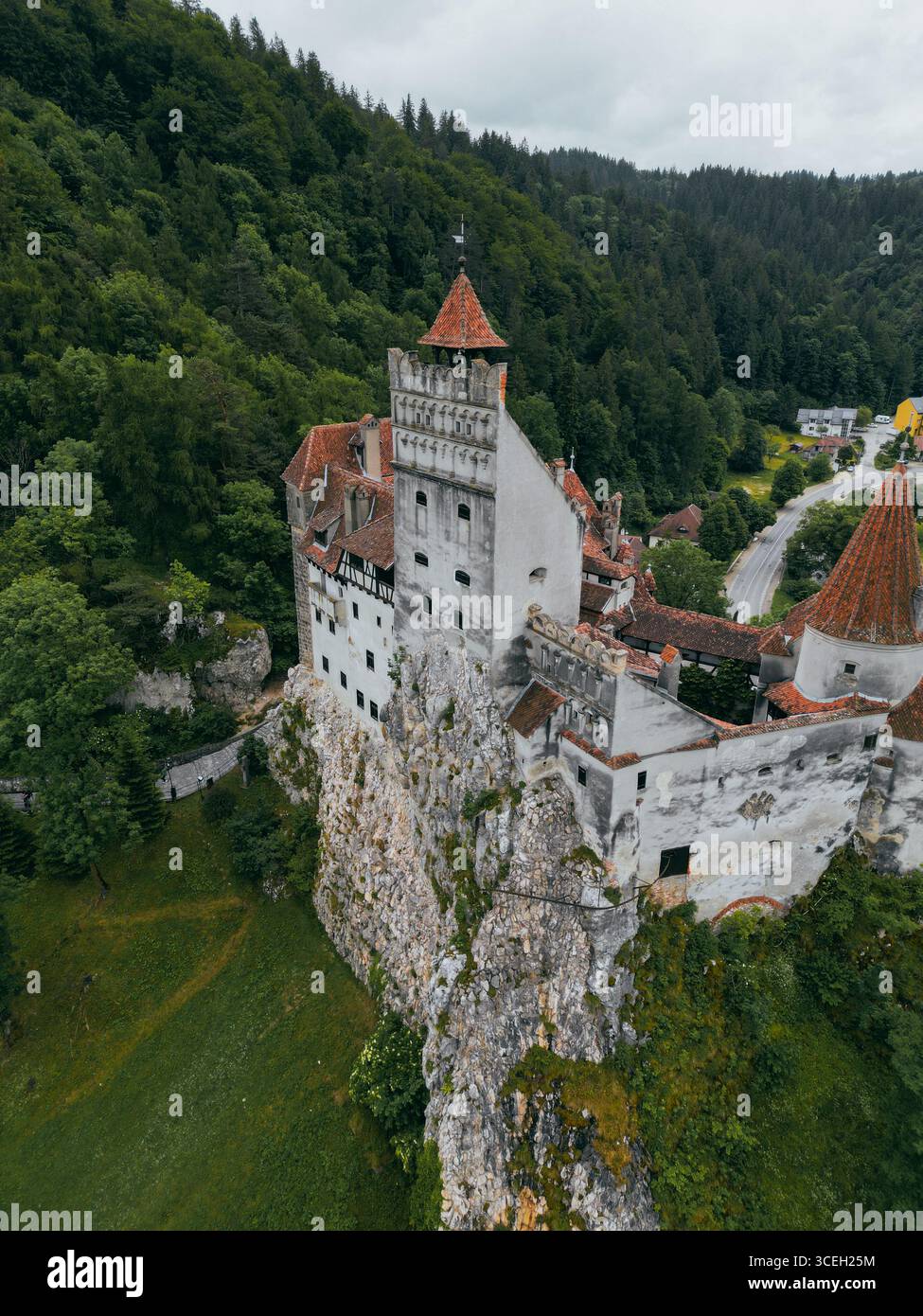 Blick aus der Vogelperspektive auf die imposante Burg Bran auf einem felsigen Felsen, umgeben von grünen Wäldern, unter einem bewölkten Himmel, Bran, Județul Brașov, Rumänien. Stockfoto