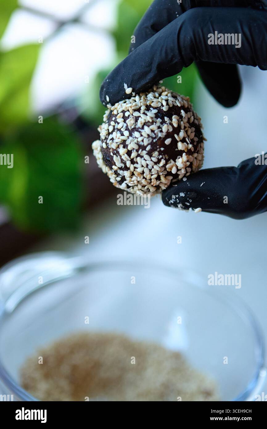 Vegane Süßkugel aus Datteln, Nüssen, Rosinen und Kakao in der Hand Stockfoto