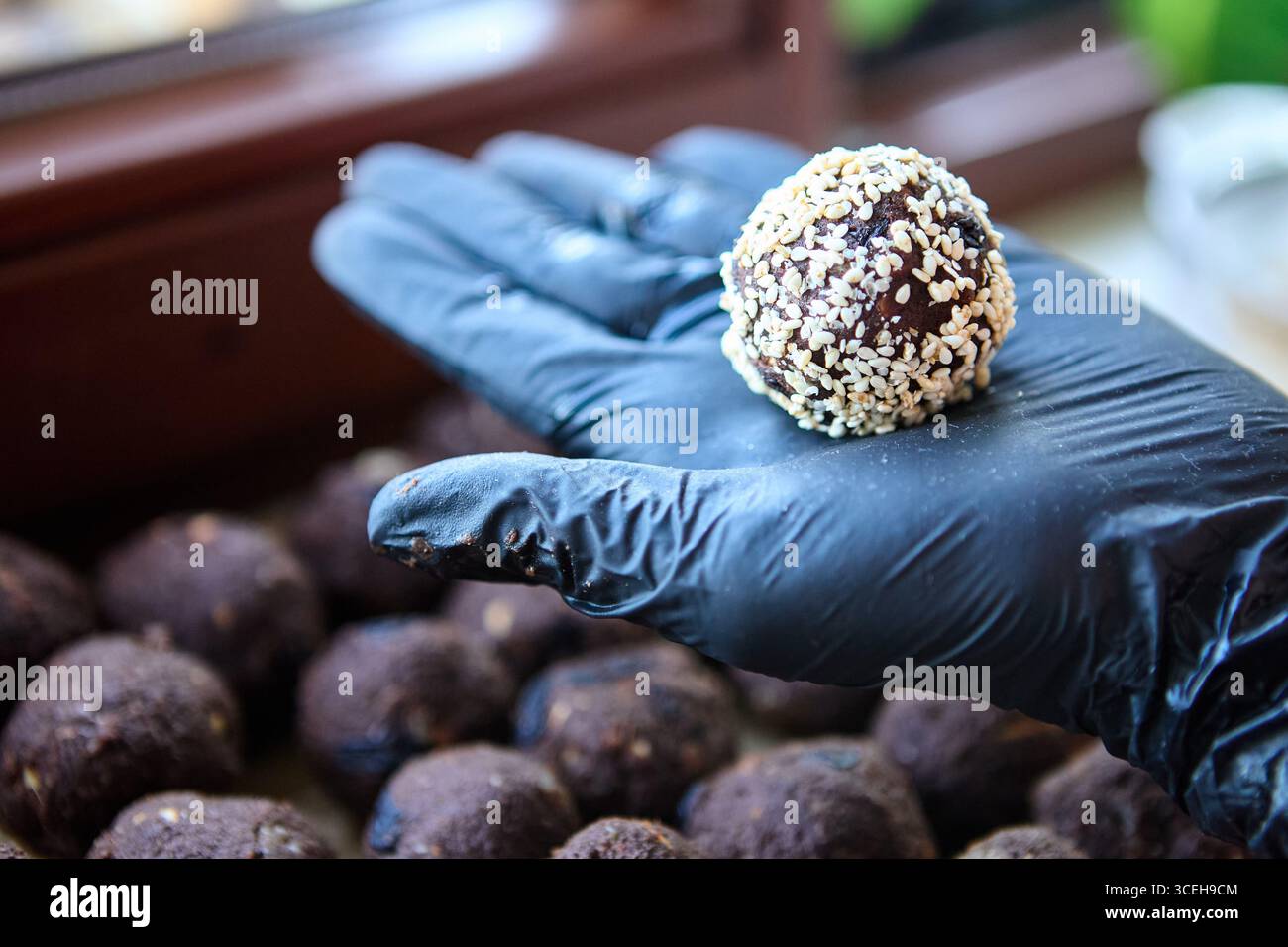 Hausgemachte vegane Süßigkeiten aus Datteln, Nüssen, Rosinen und Kakao in Handhandschuhen Stockfoto