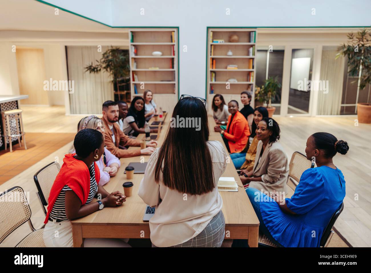 Eine Gruppe von Fachleuten aus einer Werbeagentur sitzt an einem Konferenztisch für ein Team-Briefing. Sie sind in einem kollaborativen Disku engagiert Stockfoto