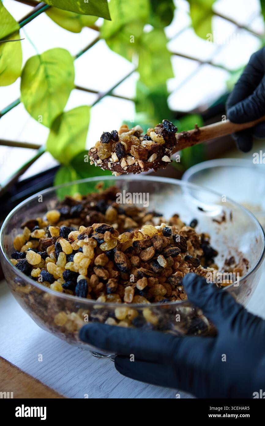Holzlöffel mit einer Mischung aus gehackten Datteln, Rosinen und Nüssen für natürliche rohe Süßigkeiten Stockfoto