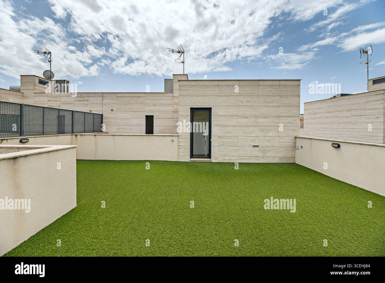 Minimalistisches Penthaus-Terrasse, auf der weißer Marmor mit flaschengrünem Kunstrasen in weichem Flaschengrün verflochten ist Stockfoto