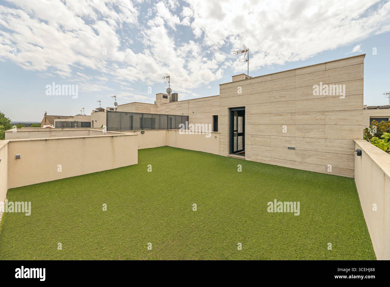 Moderne Penthaus-Terrasse, auf der cremefarbene Marmor und jugendlich gefärbter Kunstrasen chromatische Harmonie schaffen Stockfoto