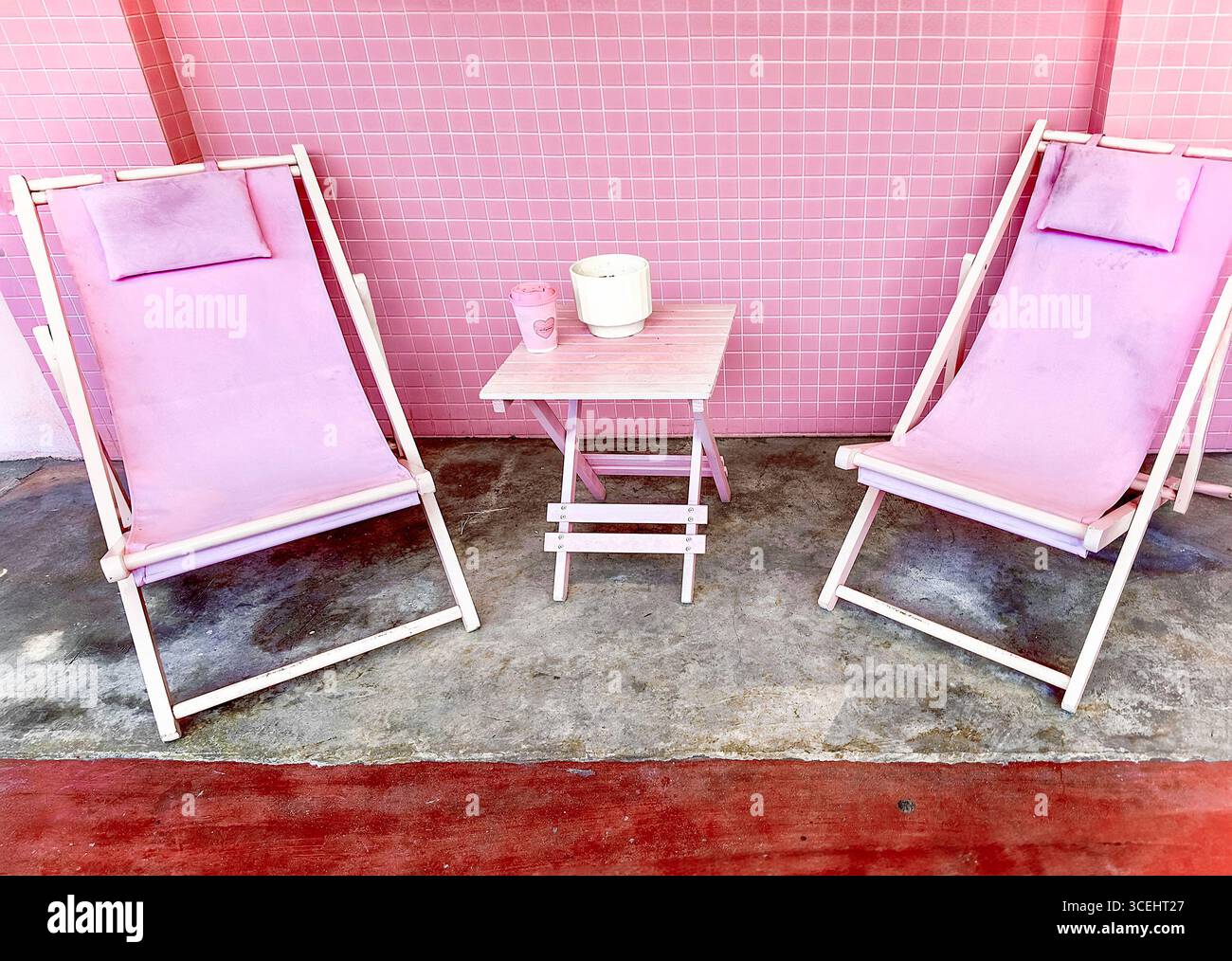 Zwei pastellrosa Liegestühle und kleiner Tisch vor rosa gefliesten Wänden The Hug Store Jalan Penang, George Town penang malaysia Stockfoto