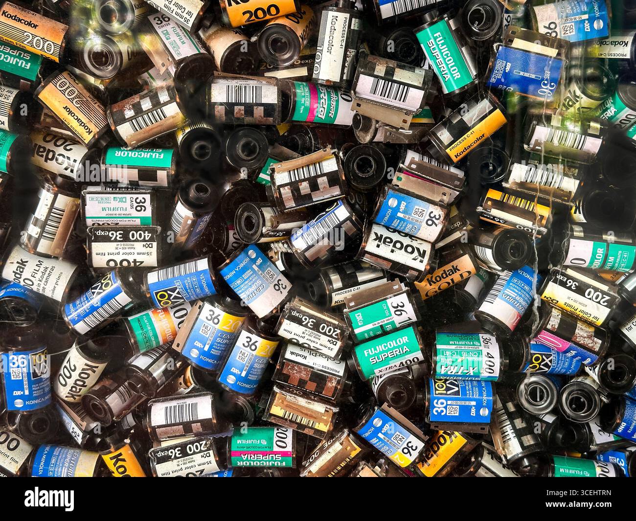 Eine Sammlung verschiedener farbenfroher, leerer 35-mm-Filmkanister von verschiedenen Marken kodak fujicolor in einer zufälligen Anordnung am Schaufenster in singapur - Smartphone-aufgenommenes Stockfoto