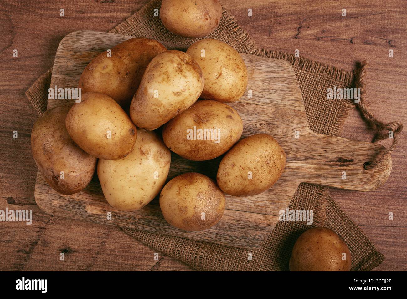 Rohe Kartoffeln, verstreut auf einem Schneidebrett, Nahaufnahme, keine Leute Stockfoto