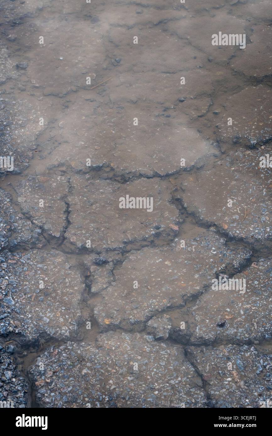 Gebrochene Asphaltstraße, Nasse Risse Form Oberfläche. Stockfoto