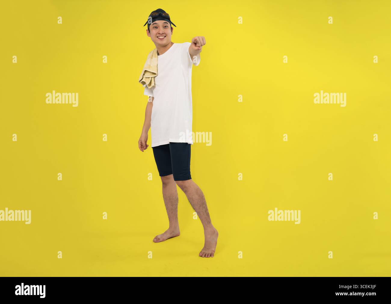 Junger Schwimmer mit Handtuch, das in hellem Studio positive Wirkung zeigt Stockfoto