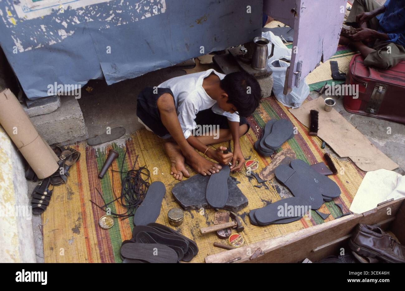 Indisches Schuhmacherkind, das auf der Straße arbeitet, Tamil Nadu, Indien Stockfoto