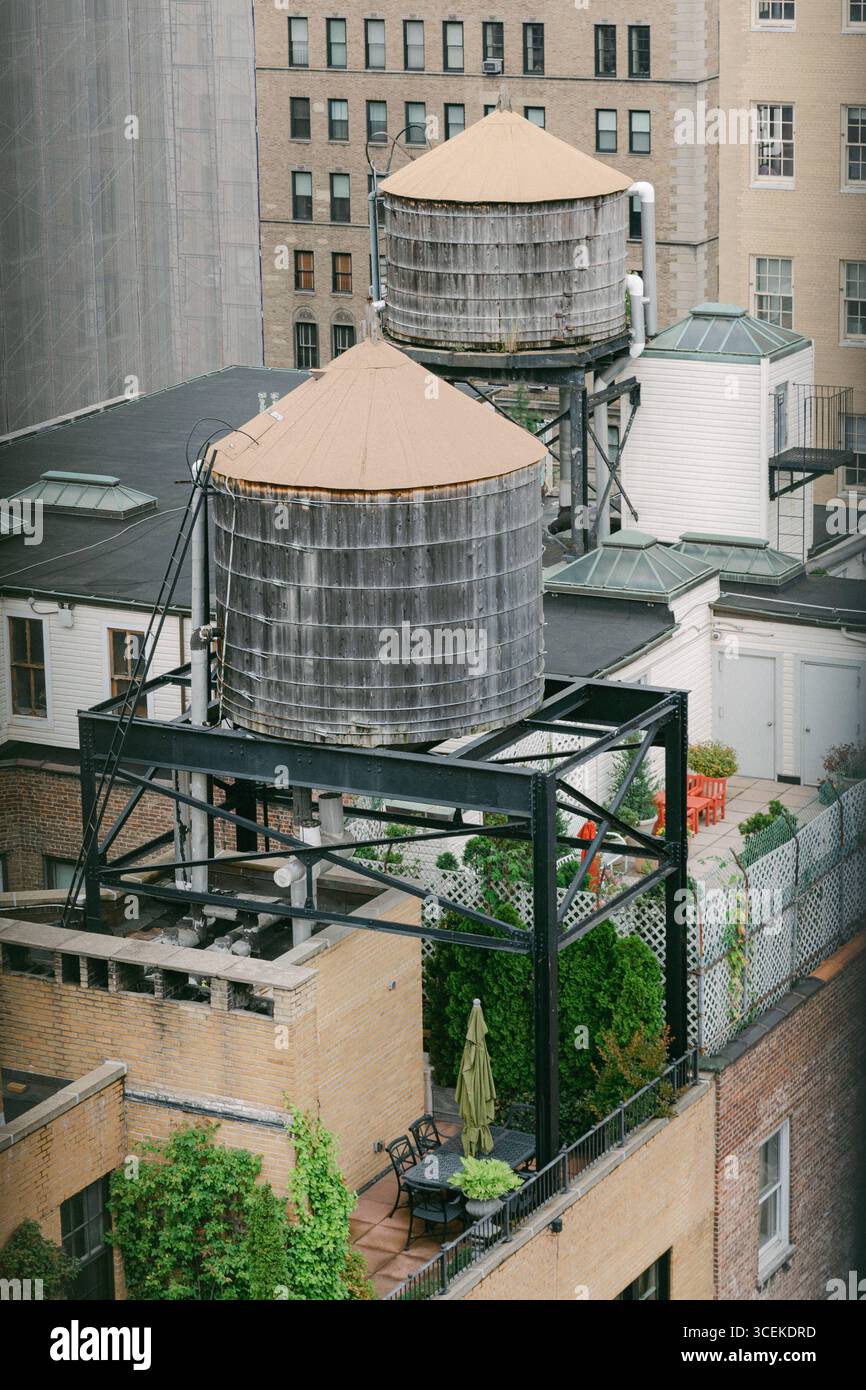 Zwei hölzerne Wassertürme mit einem Dachgarten erblühen in einer lebhaften Stadtlandschaft, die das Leben und Design der Stadt veranschaulicht. Stockfoto