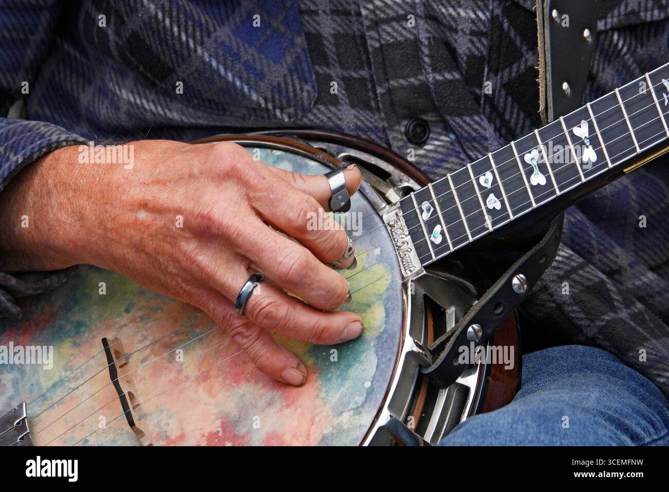 Die arthritischen Finger und die Hand eines Mannes greifen die Saiten auf einem Banjo aus, während sie eine Menge auf einer Landmesse im Zentrum von Oregon in der Nähe der Stadt Sisters unterhalten Stockfoto