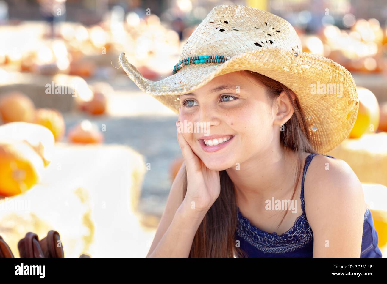 Hübsches Mädchen mit Cowboy-Hut, das den Kürbis-Patch an einem sonnigen Herbsttag genießt. Stockfoto