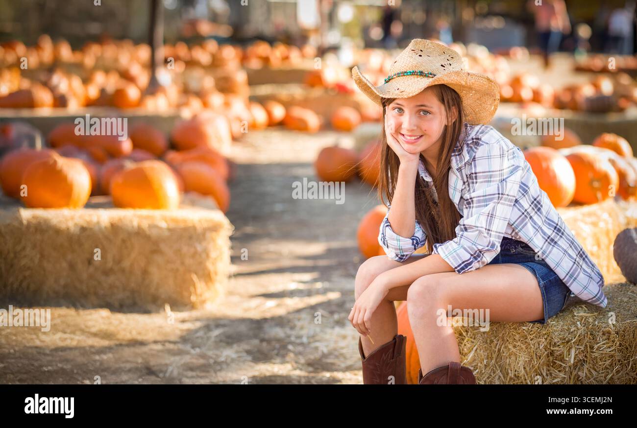 Hübsches Mädchen mit Cowboy-Hut, das den Kürbis-Patch an einem sonnigen Herbsttag genießt. Stockfoto
