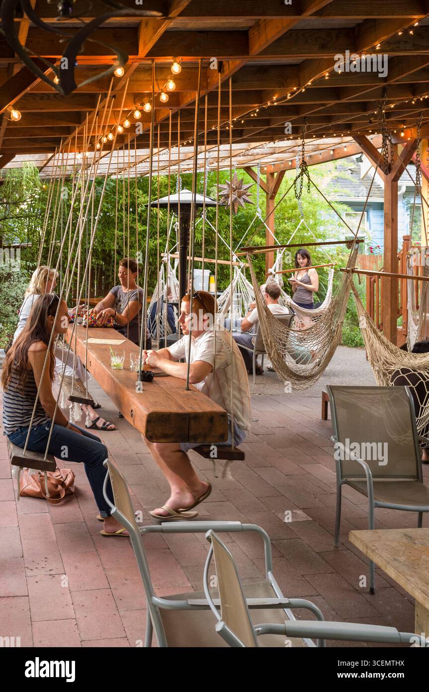 Leute sitzen in Hängematten und Schaukeln an der Bungalow Bar, Portland, Multnomah, Oregon, USA Stockfoto