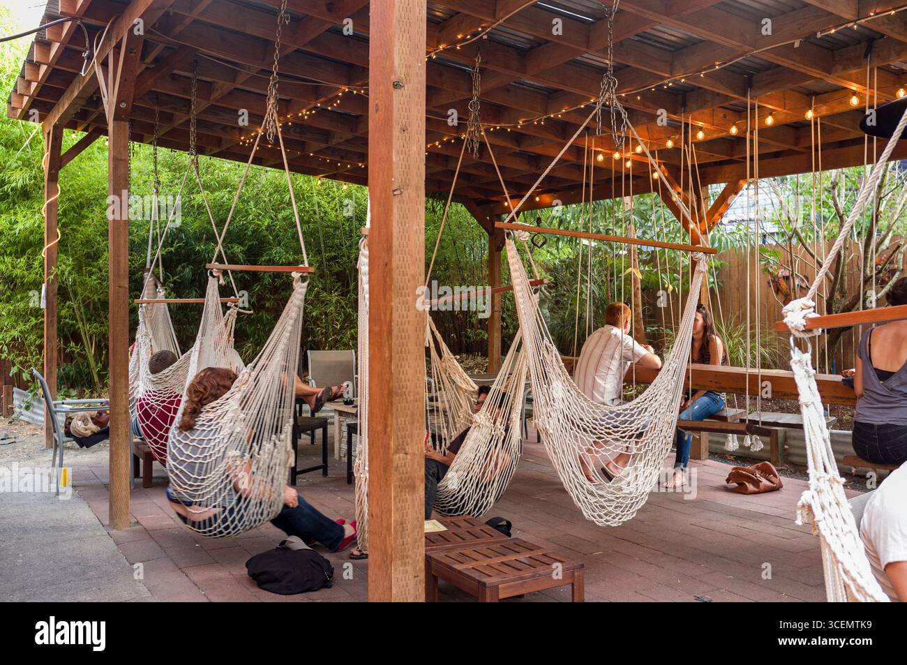 Leute sitzen in Hängematten und Schaukeln an der Bungalow Bar, Portland, Multnomah, Oregon, USA Stockfoto