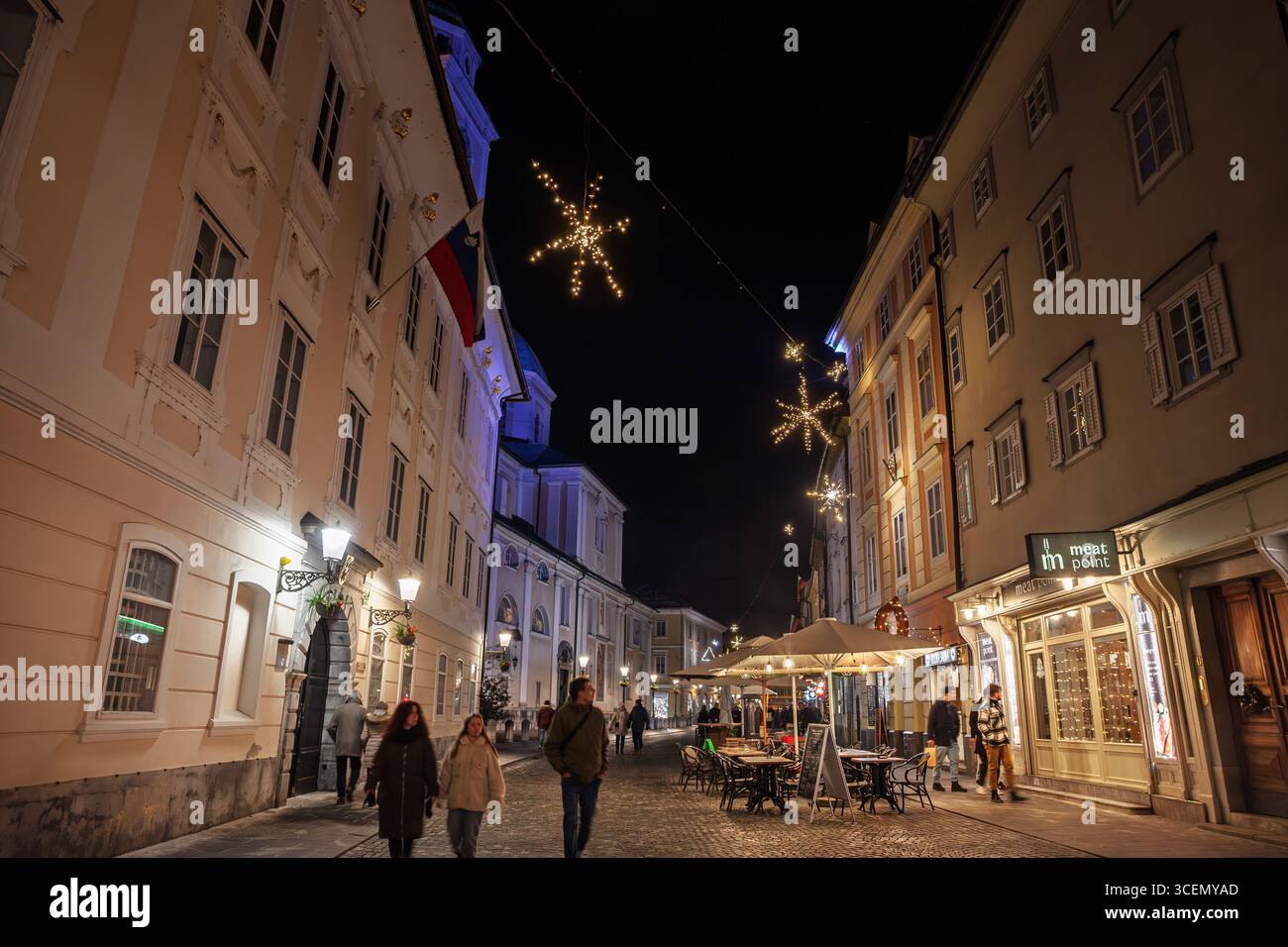 LJUBLJANA, SLOWENIEN - 17. DEZEMBER 2024: Abendblick auf Ciril Metodov trg im Stadtzentrum von Ljubljana zur weihnachtszeit. Die Schneeflockenbeleuchtung reicht zwischen h Stockfoto