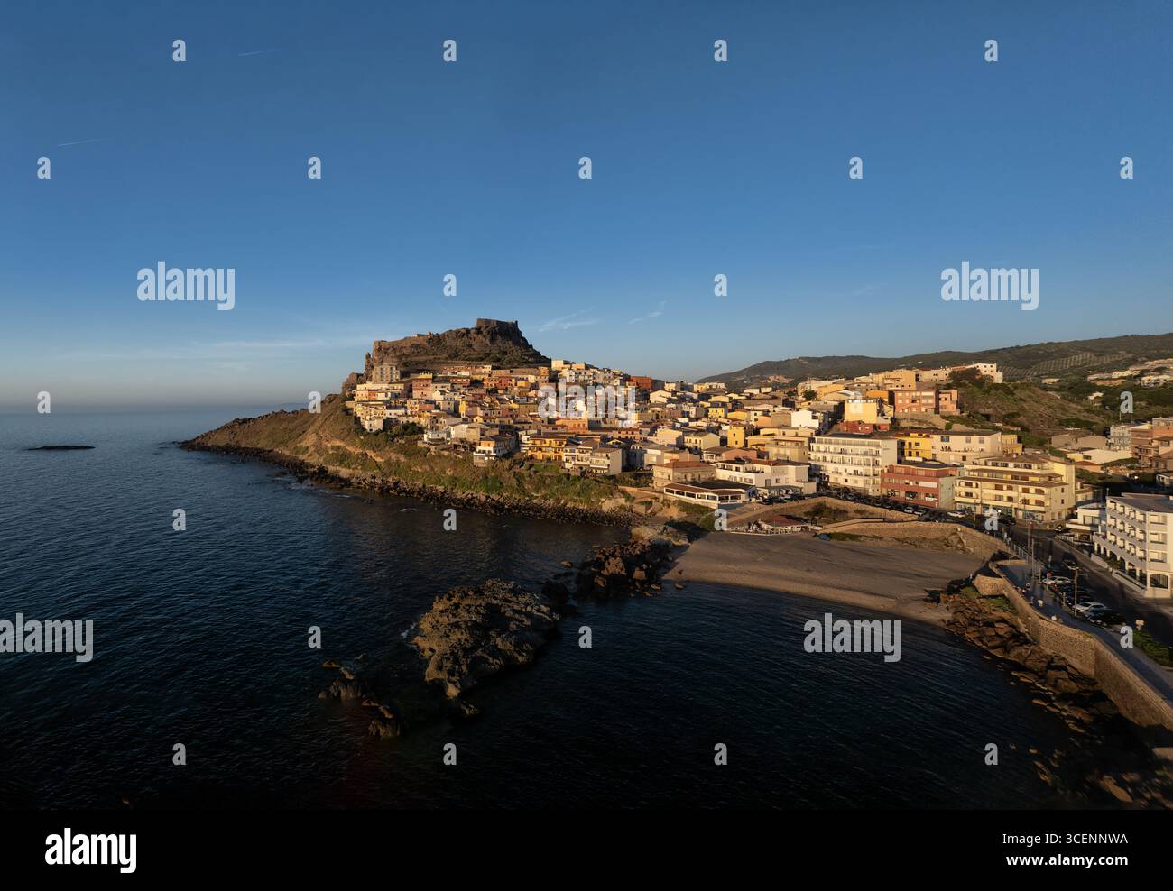Aus der Vogelperspektive auf das alte Castello dei Doria wacht über den Terrakotta-Dächern von Castelsardo, umgeben vom azurblauen Meer, Castelsardo, Sardinien, Italien. Stockfoto