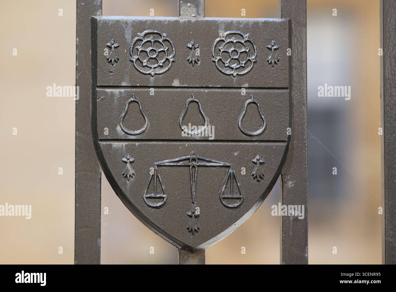 Verziertes Schild-Emblem mit Birnen- und Skalenmotiven am Metalltor. Oxford, England Stockfoto
