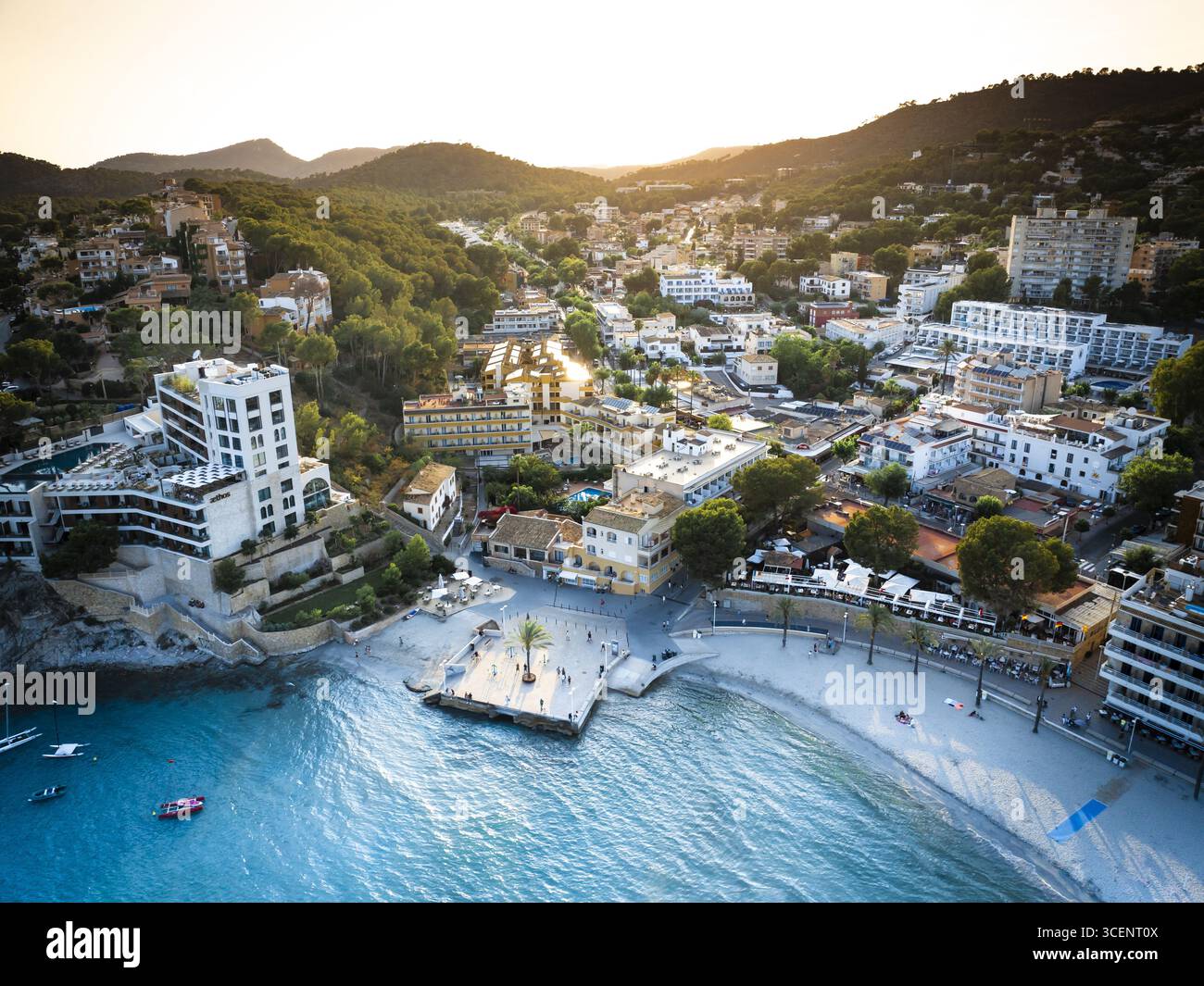 Blick aus der Vogelperspektive auf den Strand und die Gebäude von Peguera, eingebettet zwischen grünen Hügeln und dem glitzernden Meer, Peguera, Illes Balears, Spanien Stockfoto