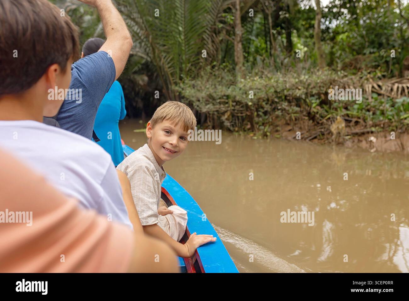 Glückliche europäische Familie mit Kindern, Besuch des Mekong Flusses in Vietnam an einem Sommertag, Bootsfahrt, lokale Gewohnheiten Stockfoto