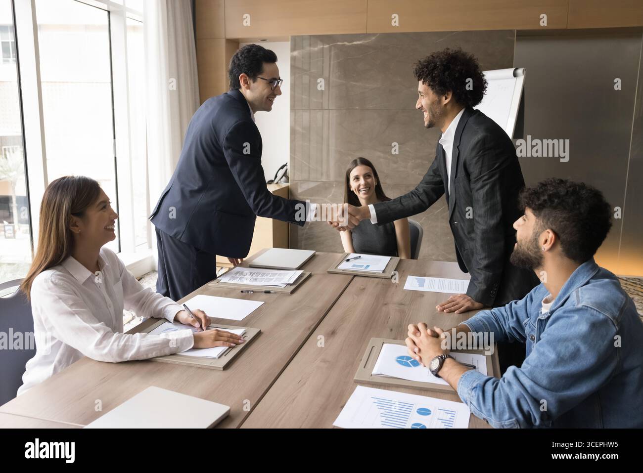 Zwei junge Männer, die bei der Direktorenversammlung Hand schütteln Stockfoto