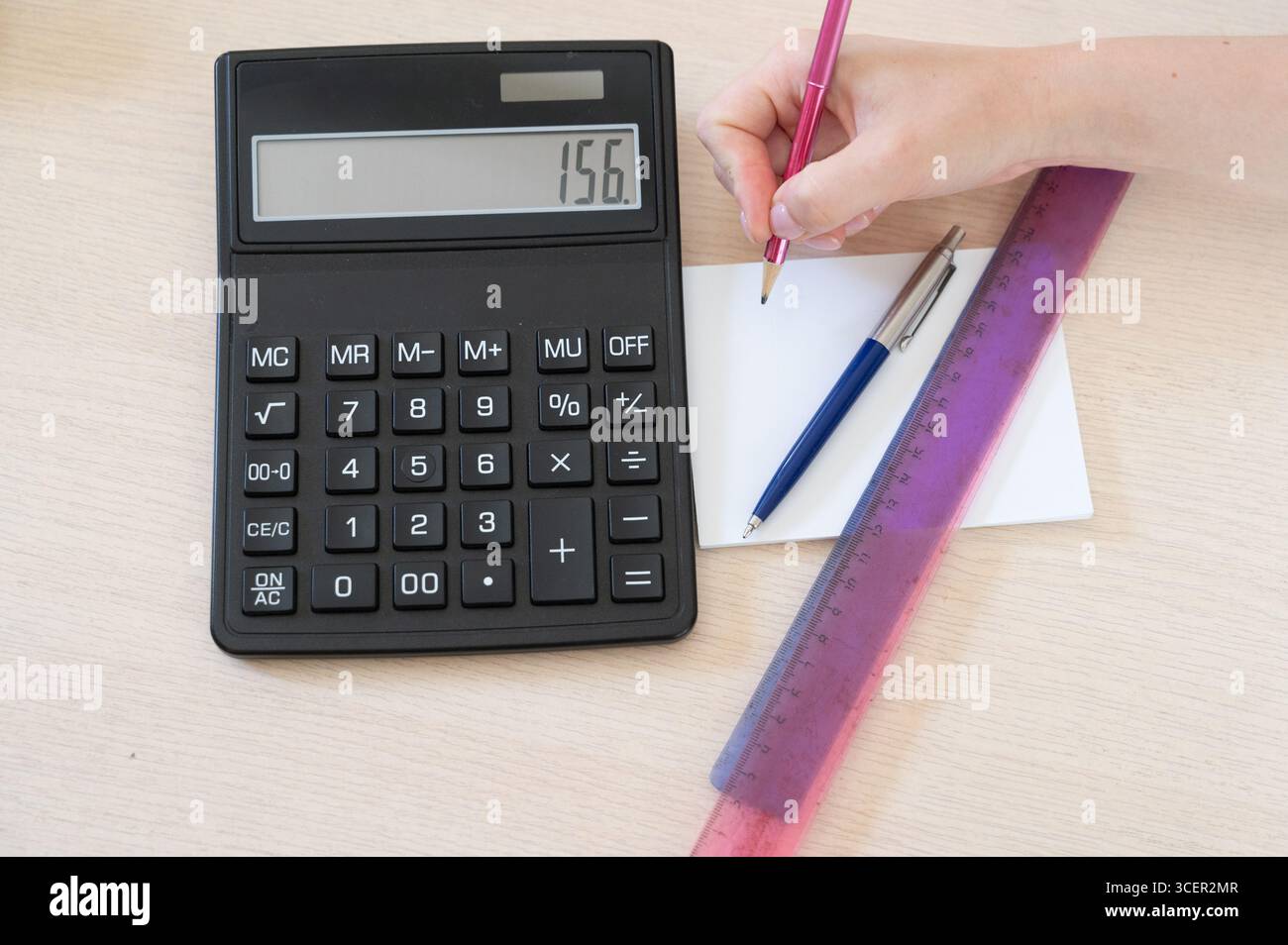 Ein funktionaler Schreibtisch verfügt über einen Taschenrechner, Stifte und ein Lineal für mathematische Aufgaben, die die Gesamtproduktivität steigern Stockfoto