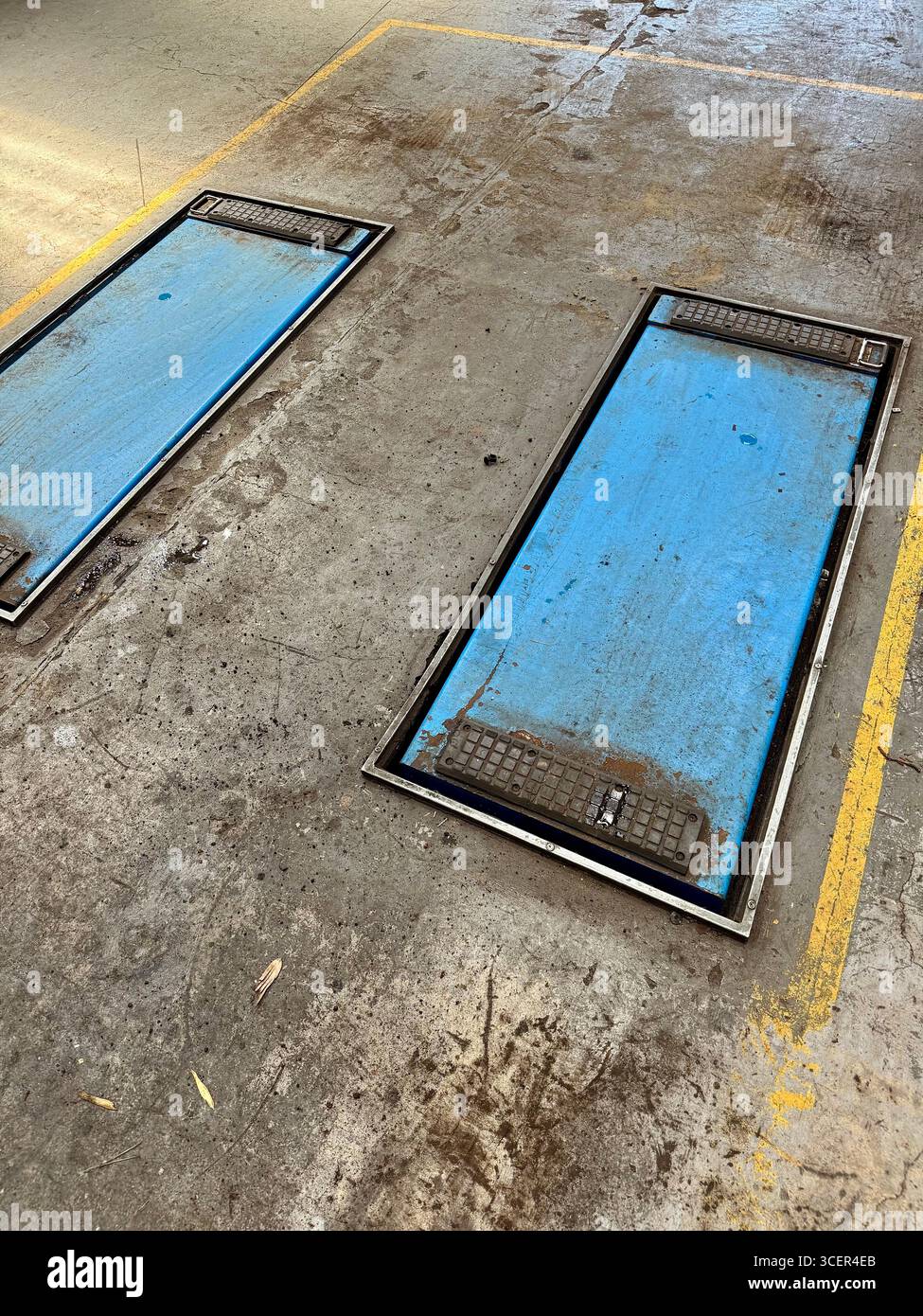 Werkstattboden mit Inspektionsrampen für Fahrzeugwartung und -Reparatur. - Smartphone-aufgenommenes Stockfoto