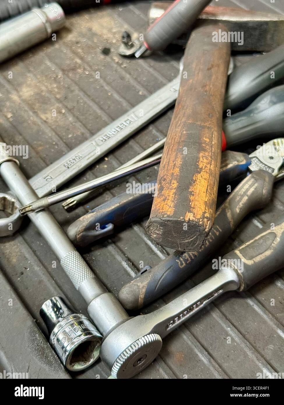 Verschiedene mechanische Werkzeuge wie Hammer, Schraubenschlüssel und Schraubendreher in einer Autowerkstatt. Stockfoto