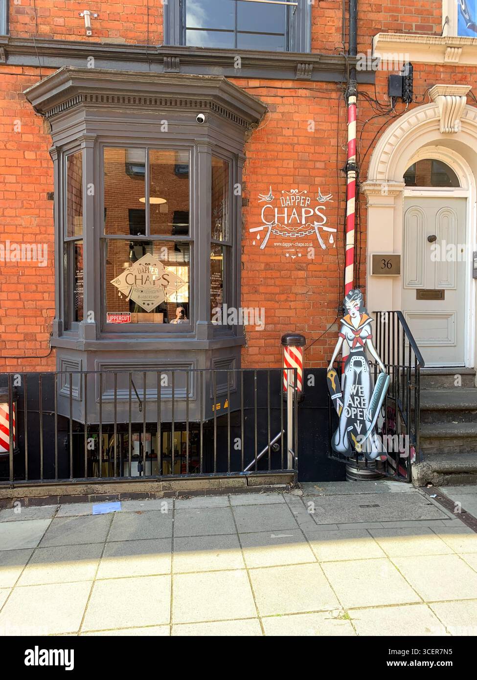 Friseurladen Derngate Northampton Schild Chaps Straßengebäude Stange rot weiß geschnitten Haare Leute netter freundlicher Friseur Pflaster Türstuhl innen Farbe - Smartphone-aufgenommenes Stockfoto