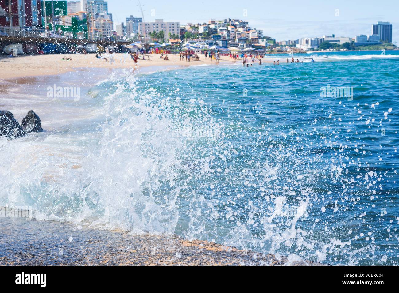 Spritzer einer Strandwelle, die hart gegen einen Zementpfeiler kracht. Wintersaison. Kraft der Natur. Stockfoto