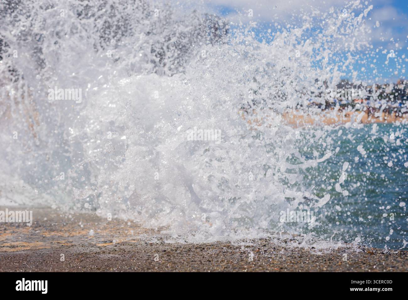 Spritzer einer Strandwelle, die hart gegen einen Zementpfeiler kracht. Wintersaison. Kraft der Natur. Stockfoto