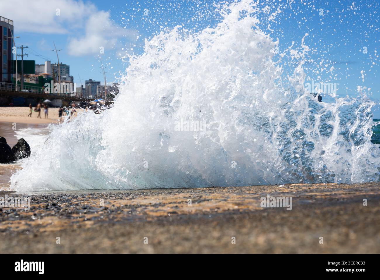 Spritzer einer Strandwelle, die hart gegen einen Zementpfeiler kracht. Wintersaison. Kraft der Natur. Stockfoto