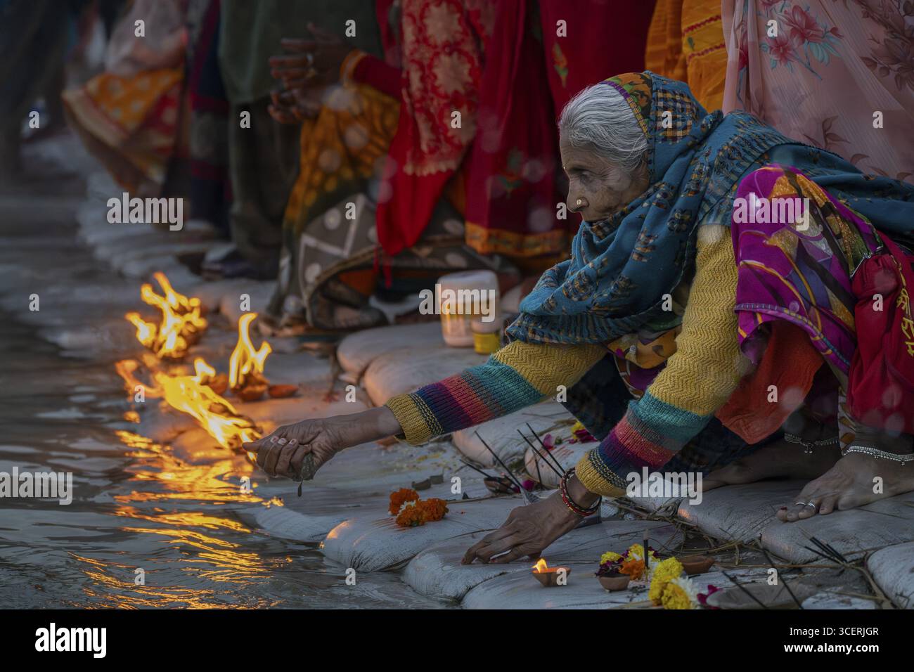 Ältere Frau, die ein Ritual am Wasser durchführt, mit Kerzen, Maha Kumbh Mela, Arail Uparhar, Karchana, Uttar Pradesh, Indien Stockfoto