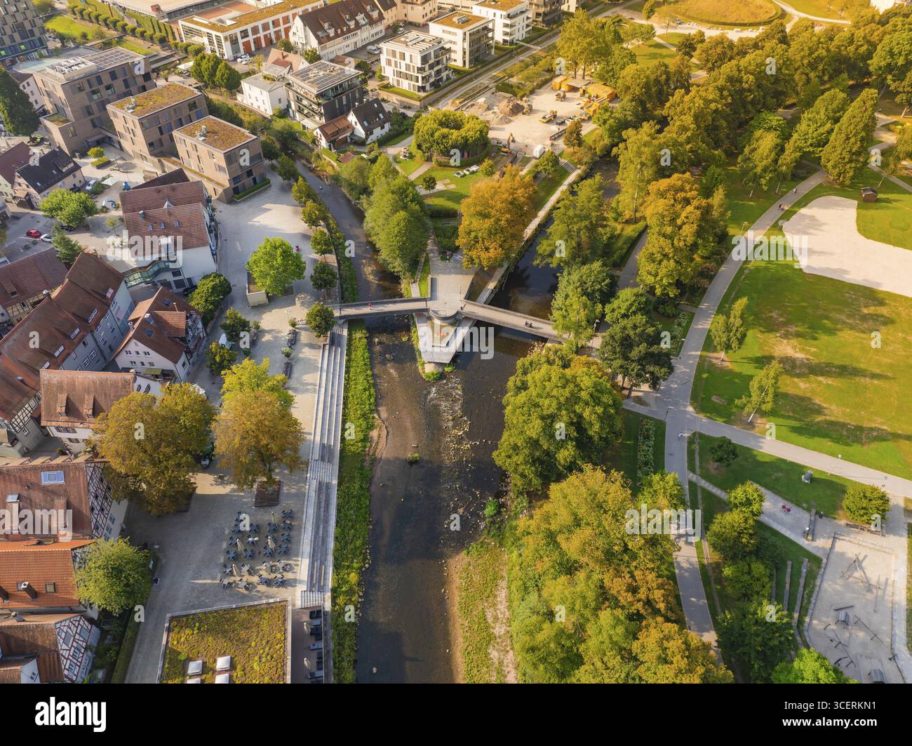 Blick aus der Vogelperspektive auf einen Park mit Fluss und Brücke, umgeben von Herbstlaub und Gebäuden, Nagold, Bezirk Calw, Schwarzwald, Deutschland Stockfoto