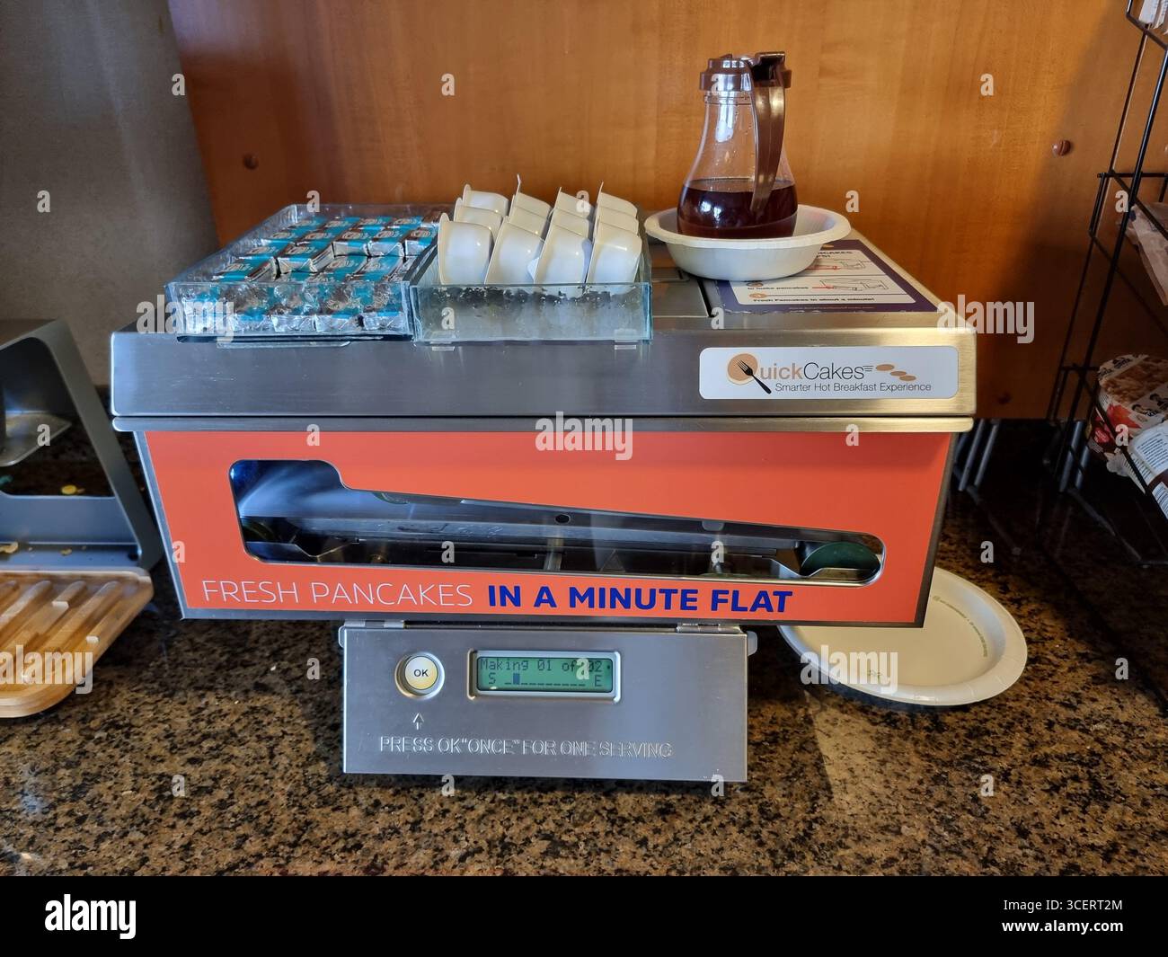 QuickCakes: Maschine zum Zubereiten von „frischen Pfannkuchen in einer Minute“; darauf platzierte Sirup und Butter; im Frühstücksraum des Hotels Stockfoto