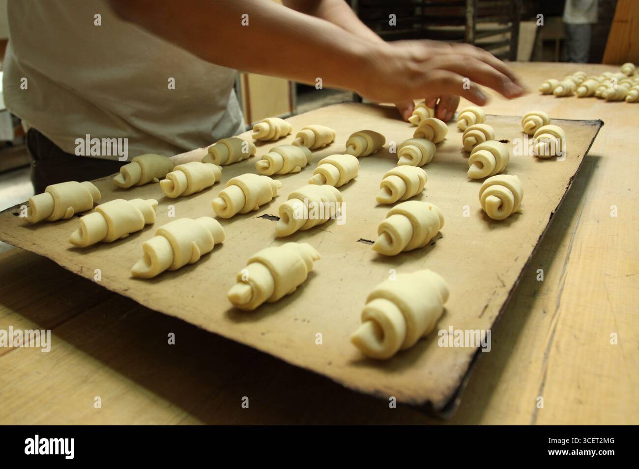 Nahaufnahme von Bäckerhänden, die Croissants zubereiten Stockfoto